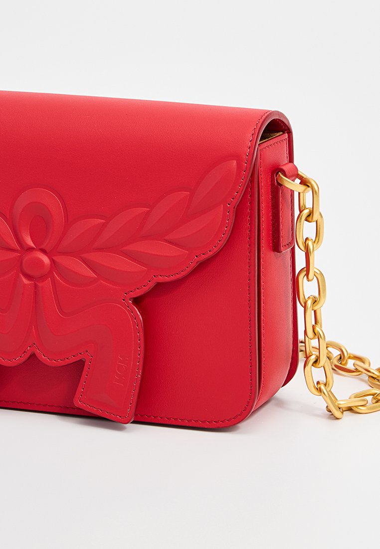 Rote Lederhandtasche mit erhabenem Blumenmuster auf dem Deckel und goldener Kettenriemen. Merkmale sind die rechteckige Form und die glatte Textur.