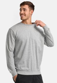 Sudadera gris hecha de material suave, con cuello redondo, mangas largas, puños acanalados y un sutil detalle del logo en el pecho.