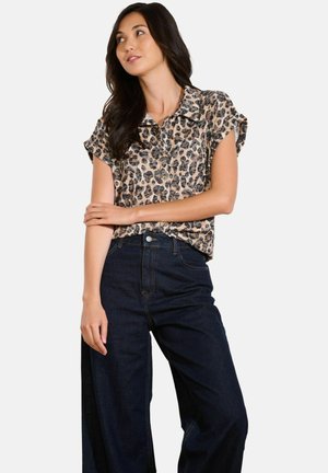 Leopard print short-sleeve shirt made of lightweight fabric, featuring a collared neckline and button-down front, paired with dark wide-leg jeans.