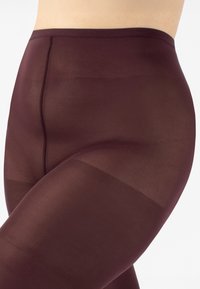 Leggings bordeaux opachi con texture liscia, vita alta e design senza cuciture, che mostrano un colore e una vestibilità uniformi lungo le gambe.