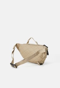 Natūralios spalvos siuvinėta kryžminių pečių rankinė, turinti trikampio formą, reguliuojamą petnešą ir logotipo detales. Turinti viršutinį rankeną ir užtrauktuko uždarymą.