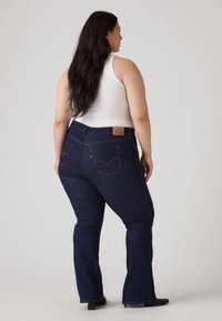 Mørkeblå vide jeans med middels høy midje, laget av denim. Har klassisk søm og en lær-logo på baksiden.