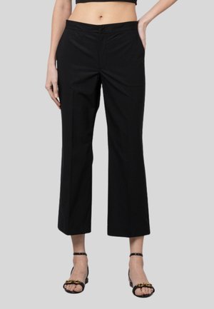Pantalones negros de pierna ancha con una textura suave, que cuentan con una cintura y bolsillos laterales. Combinados con sandalias negras de tiras.