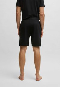 Pantaloni sportivi neri realizzati in tessuto liscio e leggero. Presentano una vita elastica e un design semplice senza motivi visibili.