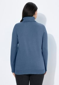 Sininen korkeakauluksinen neulepusero, jossa on pitkät hihat, ribbireunus kauluksessa ja helman kohdalla, sekä tekstiilikuosi alaosassa ja kapea muoto.