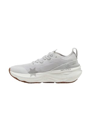Scarpa atletica grigia chiara con una tomaia in rete rigata, suola bianca con un accento a forma di stella e un tallone testurizzato per aderenza e supporto.