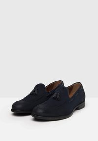 Mocassini in suede blu navy con dettagli a frange, fodera interna in pelle, cuciture decorative e suola in gomma nera bassa e arrotondata.