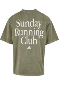 Olivově zelené tričko s krátkým rukávem a bílým textem "Sunday Running Club" a malým logem "Another Cotton Lab" na zadní straně.