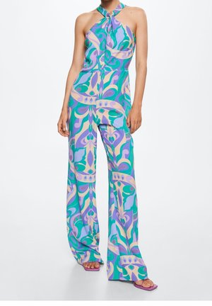 Mono halter colorido en púrpura, verde y crema con un estampado floral. La tela tiene una textura suave, con pantalones anchos y un escote anudado.