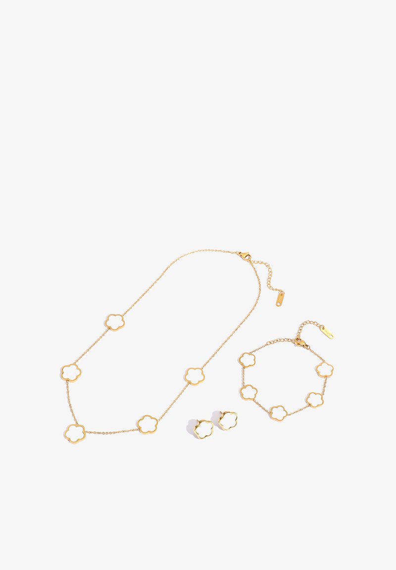 Gold jewelry set with white flower-shaped accents, including a necklace, bracelet, and a pair of stud earrings on a white background.