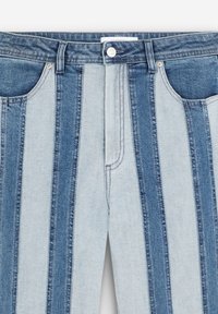 Jeans a vita alta con righe verticali in denim blu chiaro e scuro alternate, tasche frontali, passanti per cintura e chiusura a bottone.