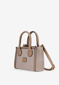 Bolso beis con tejido texturizado, acentos negros y asas dobles. Incluye una correa extraíble y una placa con el logo dorado en la parte frontal.