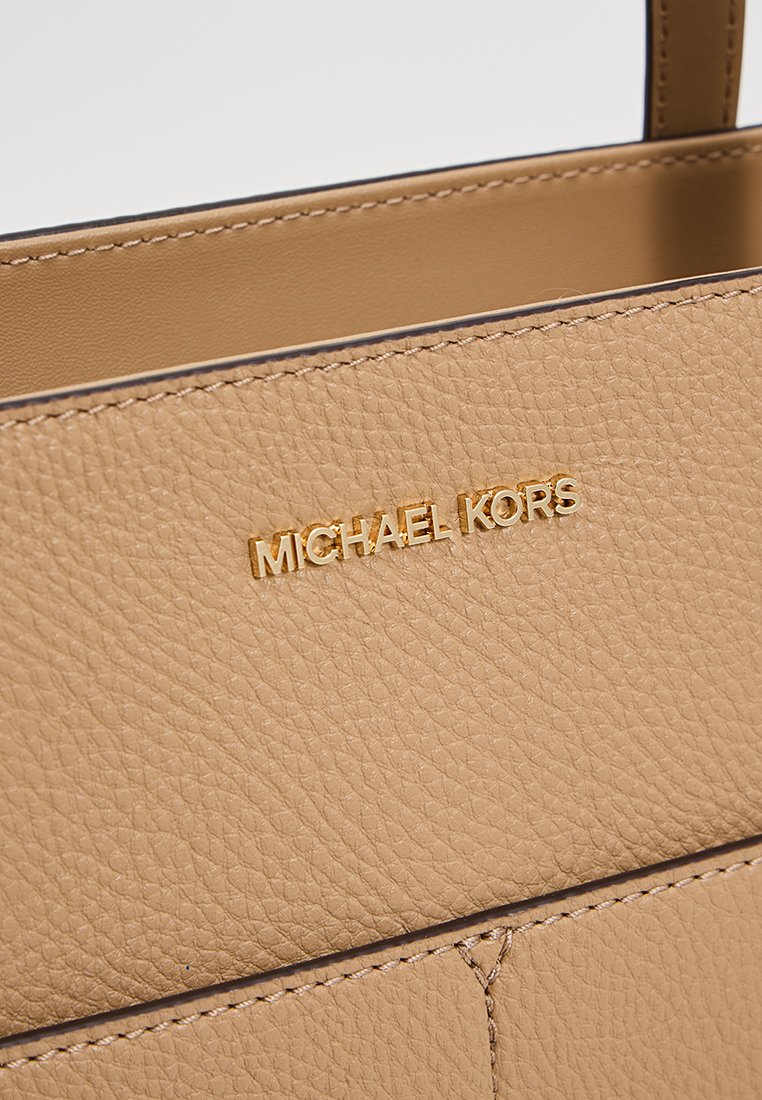 Borsa a tracolla in pelle marrone chiaro con superficie testurizzata, logo dorato e design minimalista con dettagli di cucitura puliti.