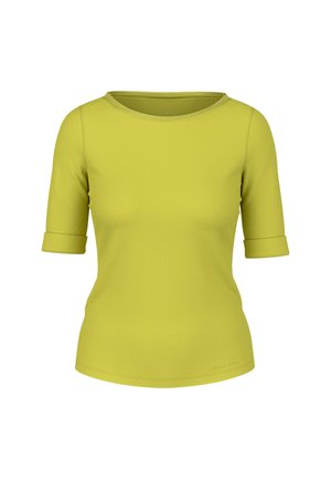 Woman wearing a lime green jacket, matching top, leopard print skirt with side slit, yellow flats, and carrying a lime green shoulder bag.