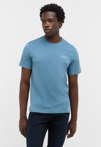 Jasnoniebieska koszulka z krótkim rękawem, wykonana z miękkiej bawełny, z okrągłym dekoltem i małym białym logo po lewej stronie klatki piersiowej.