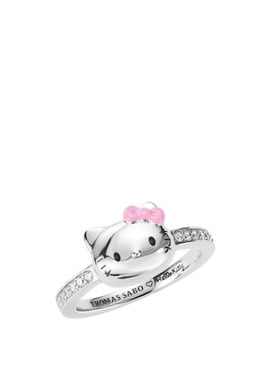 Srebrny pierścionek z twarzą Hello Kitty, u góry różowa kokardka, małe przezroczyste kamienie wzdłuż obrączki oraz wygrawerowany "Thomas Sabo Hello Kitty" wewnątrz.