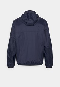 Giacca windbreaker navy con cappuccio, realizzata in tessuto leggero e liscio. Presenta polsini elasticizzati e una vestibilità ampia.