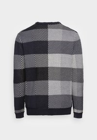 Pull en maille à manches longues avec motif à carreaux noir, gris et blanc et rayures diagonales, col et poignets côtelés.