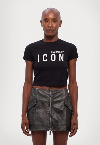 T-shirt nera cropped con testo bianco "DSQUARED2 ICON"; abbinata a una mini gonna in pelle scura con zip frontale e tasche laterali.