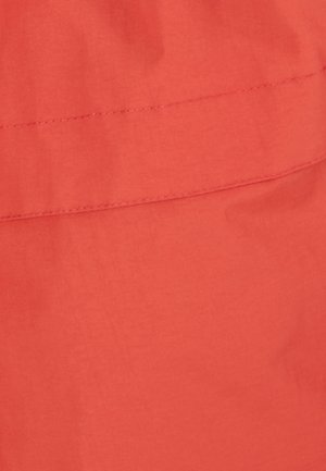 Heldere koraalkleurige stof met een gladde textuur, voorzien van een horizontale gestikte naad. De kleur is consistent zonder patronen of accenten.