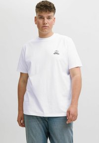 Hvid kortærmet bomulds t-shirt med et lille sort "Palm Springs" logo på brystet. Kombineret med lyseblå denim jeans.