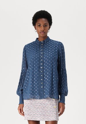 Blusa blu a maniche lunghe con una texture arricciata e delicati motivi floreali, dotata di chiusura a bottoni e colletto curvo.