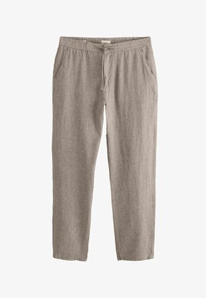 Světlé hnědé lněné kalhoty s elastickým pasem, šňůrkou na zavazování a bočními kapsami, položeny na rovné ploše na bílém pozadí.