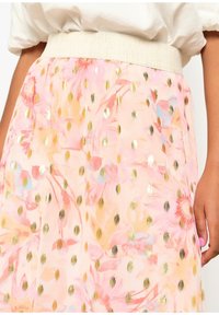 Jupe fleurie de couleur rose clair avec des accents de pois dorés. Elle présente une taille large texturée et un tissu doux et fluide avec des motifs floraux colorés.