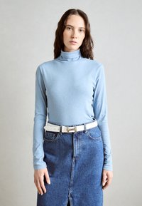 Hele sinine pikakäistega turtleneck, millega on kombineeritud sinine teksaseelik. Riietusel on valge vöö hõbedase kinnitusega.
