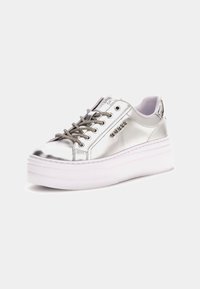 Sneaker metallic argintiu cu un finisaj neted, talpă platformă albă, ochiuri metalice și șireturi texturate pentru o aderență suplimentară.