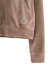 Brązowy hoodie na zamek wykonany z miękkiego materiału, z dyskretnym wzorem w kształcie litery L z dżetów na klatce piersiowej oraz kieszeniami typu kangur.