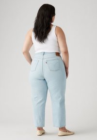 Jeans de tiro alto en azul claro con pierna recta, que presentan un parche de cuero en la parte posterior y dos bolsillos traseros.