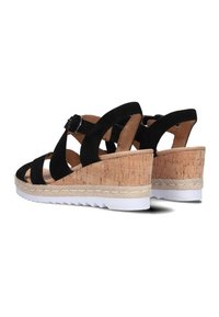 Black suede wedge sandals with cork heels, white rubber soles, and cross-strap design featuring an adjustable buckle for fit.