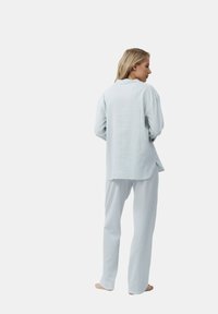 Lichtblauw gestreept loungewear-set bestaande uit een shirt met lange mouwen en bijpassende broek, gemaakt van zachte stof met een ontspannen pasvorm.