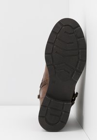 Stivale in pelle marrone con suola in gomma nera texture, dotato di zip e dettaglio con fibbia, con taglia 36 visibile sulla suola.