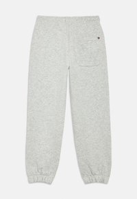 Γκρι φόρμα από μαλακό υλικό, με ελαστική μέση, στενά μανσέτες και μία πίσω τσέπη με λογότυπο.