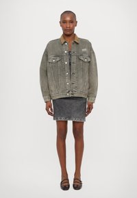 Light grey denim jacket with brown collar, front pockets, and button closures. Worn over a grey dress and paired with dark shoes.