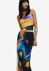 Two-piece outfit featuring a ribbed, sleeveless crop top in yellow, orange, and blue tie-dye and a matching floor-length skirt with abstract patterns.