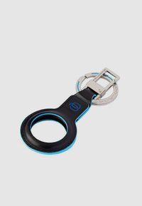 Portachiavi nero e blu con apertura circolare, ferramenta metallica e clip rettangolare. Texture liscia con accenti di colore a contrasto.
