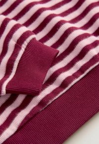 Tissu rayé bordeaux avec des rayures alternées larges roses et étroites blanches. Présente un poignet côtelé et une texture lisse. Design multicolore.