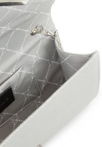 Interno di un portafoglio in pelle vegana bianca che mostra una texture liscia con un rivestimento grigio caratterizzato da un motivo geometrico. Include una tasca con zip.