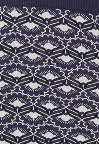 Tessuto blu navy con un intricato motivo floreale e a ventaglio bianco e nero, con fine dettaglio e una finitura a maglia testurizzata.