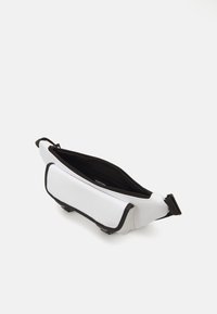 White crossbody bag with black accents, made from smooth material. Features zipper closure and a spacious interior. Flat design with minimalistic shape.