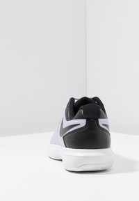 Černá a světle fialová sportovní bota s mřížkovou svrškem, texturovaným černým patním dílem a bílou podrážkou; na boku se nachází logo Nike.