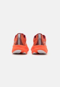 Felle oranje sportschoenen hebben een gestructureerde mesh bovenwerk, met een kastanjebruine achterkant, witte accenten en een gestructureerde, gevoerde zool.