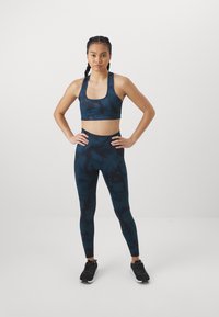 Conjunto de sujetador deportivo y leggings en azul oscuro con patrones abstractos. Fabricado en material elástico, presenta un escote cuadrado y una cintura alta.