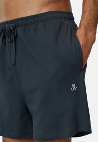 Dark navy blue swim shorts with an elastic waistband, drawstring, side pockets, and a small logo on the hem. Soft, lightweight fabric.