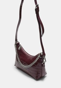 Borsa in ecopelle bordeaux con una finitura lucida effetto coccodrillo, accentata da una catena in argento e dotata di una tracolla regolabile. Caratterizzata da una chiusura con zip.