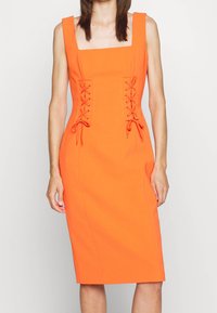Oranžové bodycon šaty se čtvercovým výstřihem, šněrováním po stranách a ke kolenům sahajícím střihem z pevné látky.