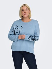 Pull tricoté bleu clair avec de grands motifs floraux noirs sur le devant, poignets et ourlet côtelés, coupe décontractée avec fentes sur les côtés.